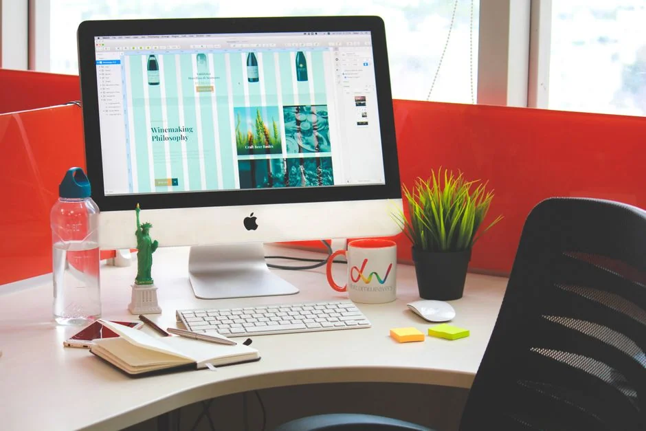 Vue rapprochée d’un carnet avec des esquisses de wireframe et un smartphone posés sur un bureau en bois.